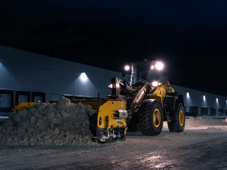Wheel loader clearing snow beside a warehouse at night in Winnipeg
